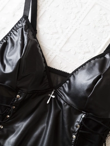 Detail eines Bodysuits aus Kunstleder mit V-Ausschnitt, Metallkreuz und seitlicher Schnürung