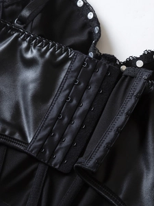 Close-up of four-row hook-and-eye closure on black faux leather corset with lace trim detail