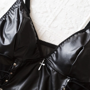 Detail von PU-Leder-Bodysuit mit Silberkreuz-Anhänger, Nieten und seitlicher Schnürung