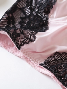 Gros plan sur de la lingerie en satin rose avec de la dentelle florale noire et lisse