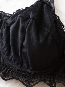 Détail de la bordure en dentelle florale noire et des bretelles en satin sur le bonnet
