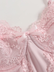 Nahaufnahme eines rosa Spitzentops mit Satinschleife und feiner floraler Spitzenkante