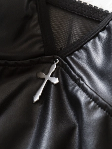 Detail aus PU-Leder und schwarzem Mesh-Patchwork mit silbernem Kreuzanhänger