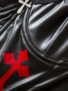 Close-up of black PU leather texture with red cross print and silver metal pendant