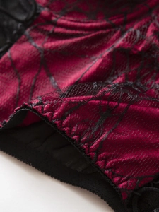 Detail of dark red satin fabric with black spiderweb lace overlay and scalloped edge