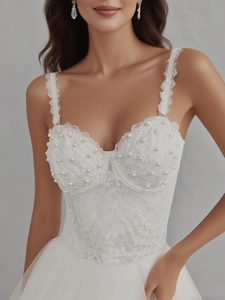 Close-up of white lace corset featuring pearl embellishments and floral embroidery details