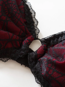 Detailed view of red mesh fabric with black lace trim and metal ring on bodysuit