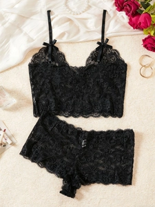 Détails de lingerie en dentelle noire avec nœuds en satin sur fond de soie blanche