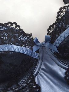 Close-up of black floral lace and blue satin fabric with a small bow detail