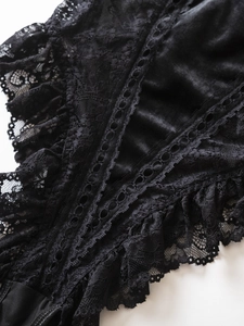 Detailed macro shot of black velvet fabric with intricate floral lace and scalloped edges