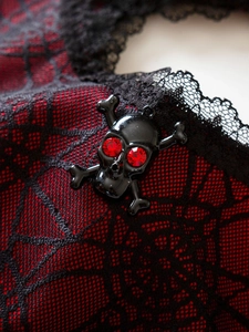 Macro detail of gothic skull pendant with red rhinestones on spiderweb lace fabric