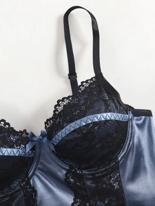 Close-up of blue satin camisole featuring black lace trim and a central bow detail