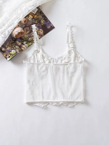 Detail of white lace corset top with adjustable straps and 3D floral lace embroidery