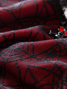 Macro shot of gothic spider web mesh fabric with red accents and ornate jewel detail