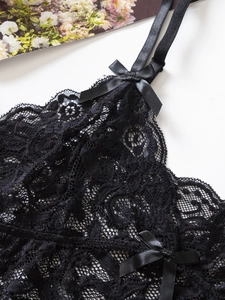 Détail de dentelle florale noire avec un nœud en satin et des bretelles réglables