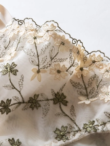 Detail of floral embroidery on mesh lingerie with scalloped edges and fine stitching
