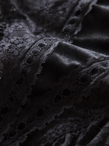 Close-up detail of luxury black floral lace stitched with soft velvet fabric texture