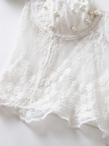 Detail of white corset featuring floral lace embroidery and elegant pearl embellishments