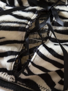 Detail of zebra faux fur fabric with elegant lace-up black ribbon and ruffle trim