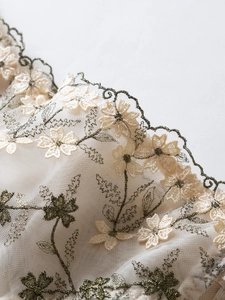 Detail of sheer mesh lace with delicate floral embroidery and scalloped edges