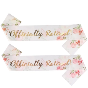 Detail view of two white satin Officially Retired sashes with pink floral and gold foil text