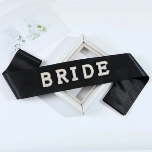 Detalle de banda de satén negro con letras de perlas BRIDE para fiesta de novia