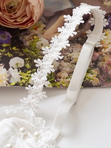 Close-up of white lace corset detail with snowflake patterns and pearl accents