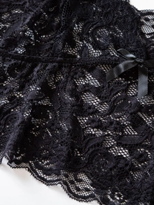 Détail de dentelle florale noire avec bords en cils et un petit noeud en satin