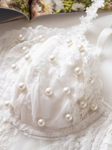 Detail shot of white lace corset with pearl embellishments and floral trim accents