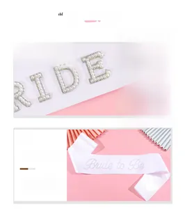 Détail de l'écharpe de mariée blanche avec lettres en perles et logo en strass brillant