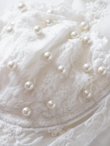 Close-up of white floral lace corset detail with elegant pearl embellishments