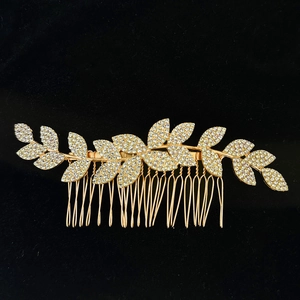 Detail of leaf-shaped hair comb with white rhinestones on a gold metal base