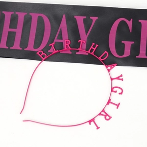 Close-up of black satin sash and pink Birthday Girl headband set for party decoration