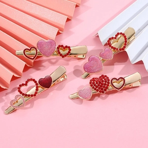 Dettaglio di quattro fermagli per capelli con cuori di cristallo rosa e rosso su metallo