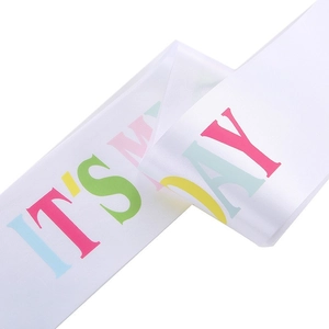 Close-up of white satin birthday sash with colorful IT'S MY DAY text and silky texture