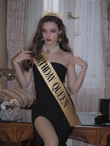 Detail of glittery Birthday Queen sash and gold rhinestone tiara on an elegant model