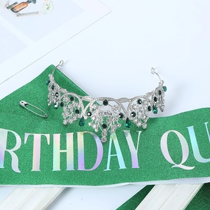 Detailed view of silver birthday queen tiara with green rhinestones on sequined sash