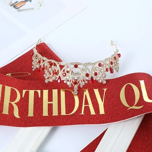 Detail of golden crystal tiara with red rhinestones and Birthday Queen glitter sash