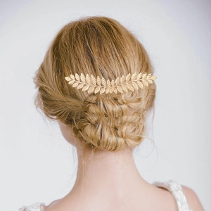 Detailed close-up of golden leaf hair comb accessory worn on an elegant updo hairstyle