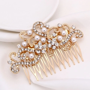 Elegant gold bridal hair comb with pearls and rhinestones on silk background