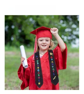 Detail of red kindergarten graduation gown with printed black sash and mortarboard cap