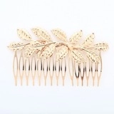 Detailed close-up of golden leaf hair comb showing hollow leaf texture and metal teeth