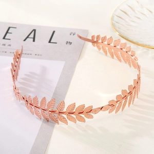 Macro shot of rose gold leaf headband with detailed olive branch texture on magazine