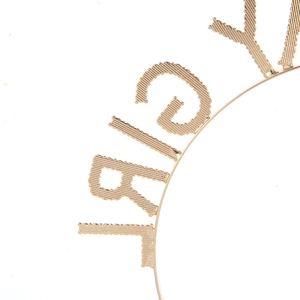 Détail du serre-tête en métal doré avec lettres GIRL et texture décorative gaufrée