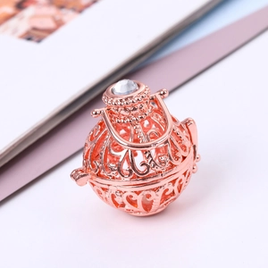 Macro-opname van de roségouden holle kooihanger met glanzende strass en bloemmotieven