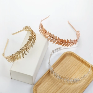 Detailed close-up of leaf headbands in gold, rose gold and silver on a wood tray