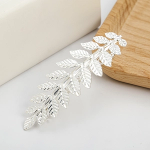 Macro shot of silver leaf hair clip with intricate branch texture and polished metal finish
