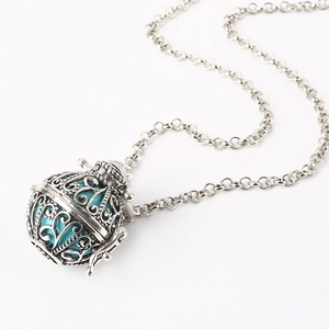 Macro detail van zilveren holle bal ketting met turquoise kraal en filigraan patronen