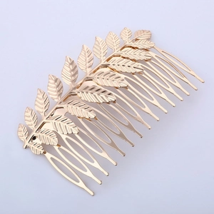 Detailed close-up of golden leaf pattern metal hair comb with textured branch details