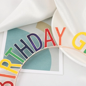 Macro detail of Birthday Girl headband with colorful enamel letters on a gold tiara frame